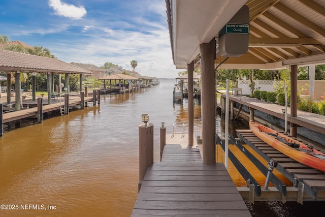 dock area featuring boat lift, a water view, and fence