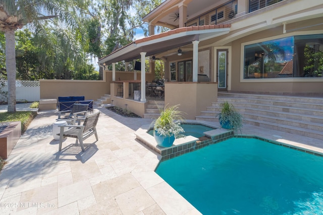 view of pool with a patio, an in ground hot tub, a ceiling fan, fence, and outdoor dining area