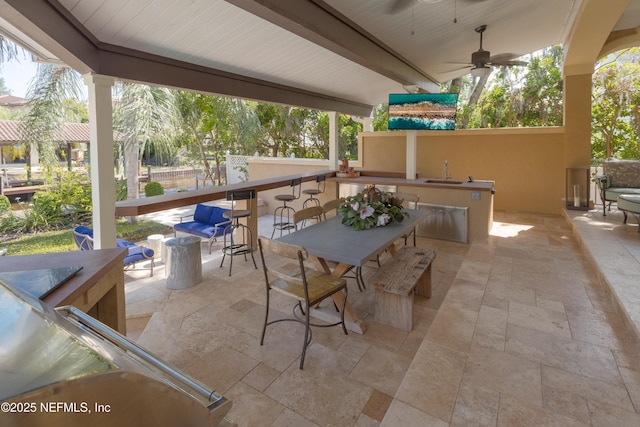 view of patio featuring ceiling fan, a sink, and fence