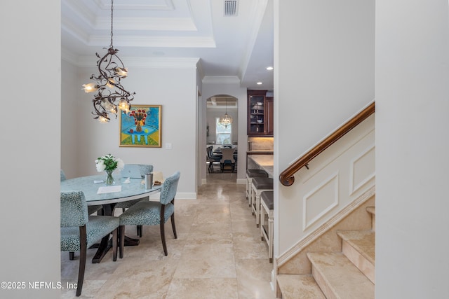 entryway with a notable chandelier, crown molding, visible vents, arched walkways, and stairs