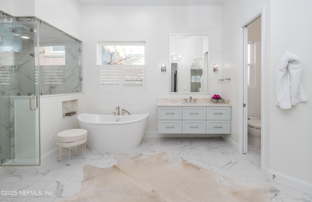 bathroom with a stall shower, baseboards, marble finish floor, a soaking tub, and vanity