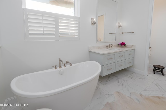 full bathroom featuring a soaking tub, baseboards, marble finish floor, and vanity