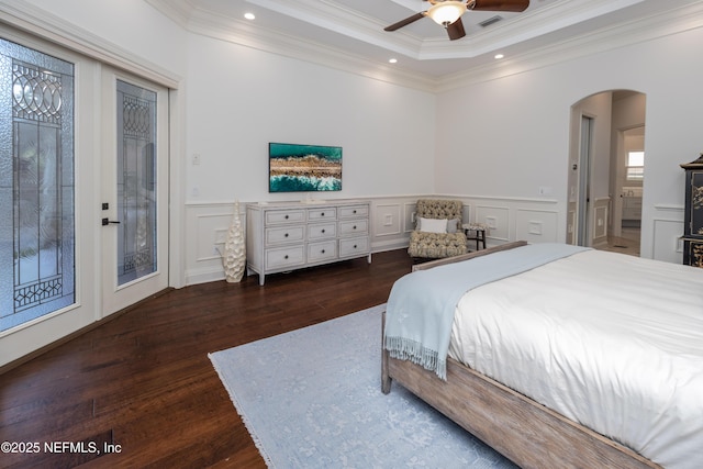 bedroom with a decorative wall, wood finished floors, ornamental molding, arched walkways, and access to outside