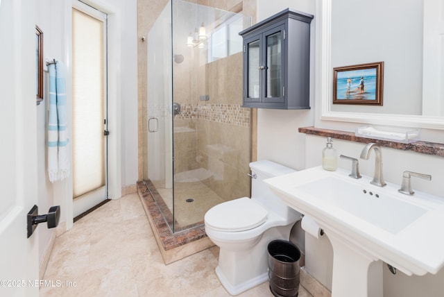 bathroom featuring a sink, toilet, a shower stall, and plenty of natural light
