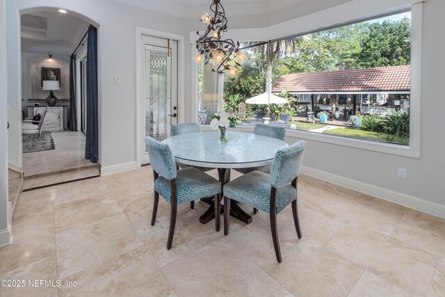 dining space with crown molding, plenty of natural light, arched walkways, and an inviting chandelier