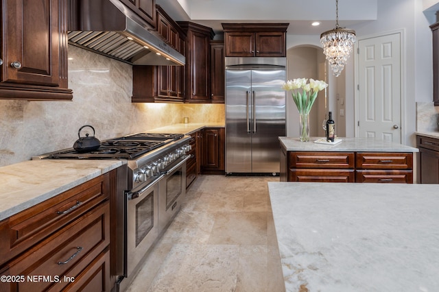 kitchen with hanging light fixtures, a chandelier, extractor fan, decorative backsplash, and high quality appliances