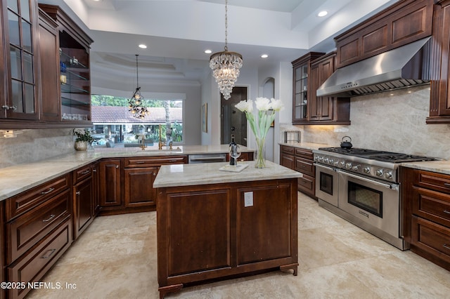 kitchen featuring ventilation hood, an inviting chandelier, a raised ceiling, and appliances with stainless steel finishes