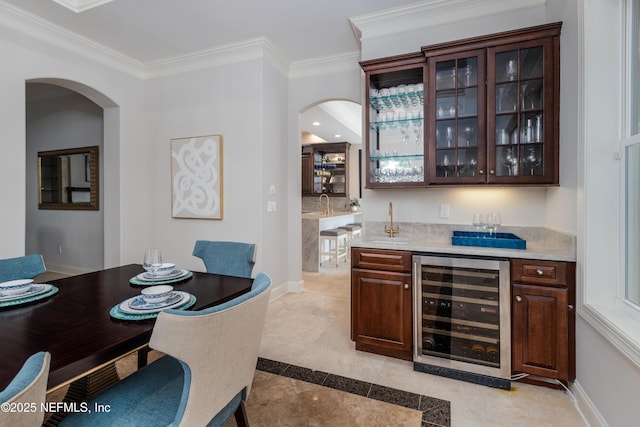 bar featuring ornamental molding, indoor wet bar, arched walkways, and wine cooler