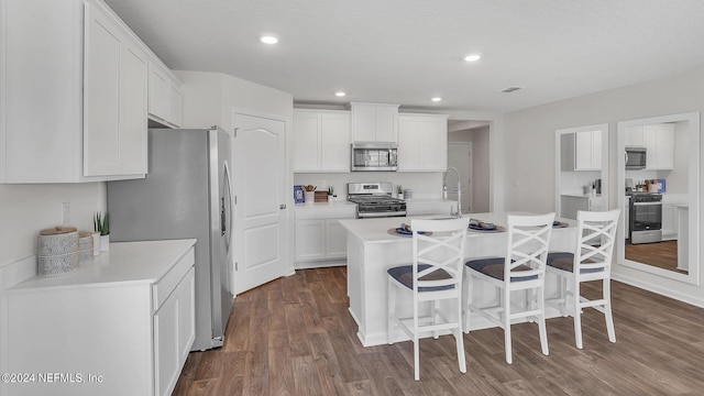 kitchen featuring white cabinetry, a breakfast bar, appliances with stainless steel finishes, and dark wood-style floors