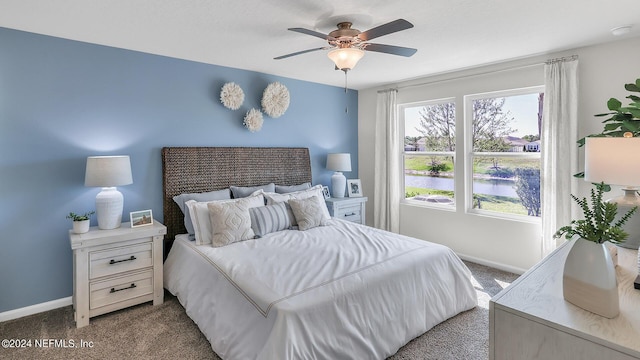 bedroom featuring carpet flooring, a water view, baseboards, and ceiling fan
