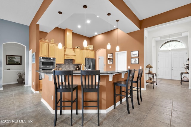 809 Ifield Rd, Saint Augustine, FL 32095 - kitchen featuring light brown cabinets, arched walkways, a breakfast bar, stainless steel double oven, and a towering ceiling