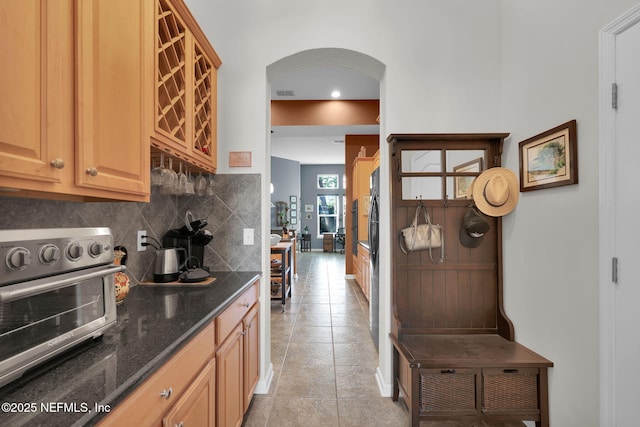 809 Ifield Rd, Saint Augustine, FL 32095 - kitchen with arched walkways, decorative backsplash, dark stone countertops, light tile patterned flooring, and recessed lighting