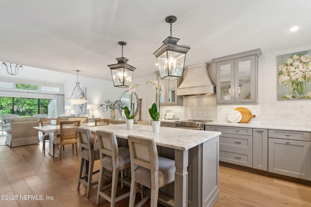 90 Players Club Villas Rd, Ponte Vedra Beach, FL 32082 - kitchen featuring an inviting chandelier, light wood finished floors, decorative backsplash, gray cabinetry, and custom range hood