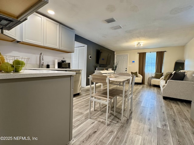 kitchen with stainless steel dishwasher, open floor plan, light wood-type flooring, and visible vents