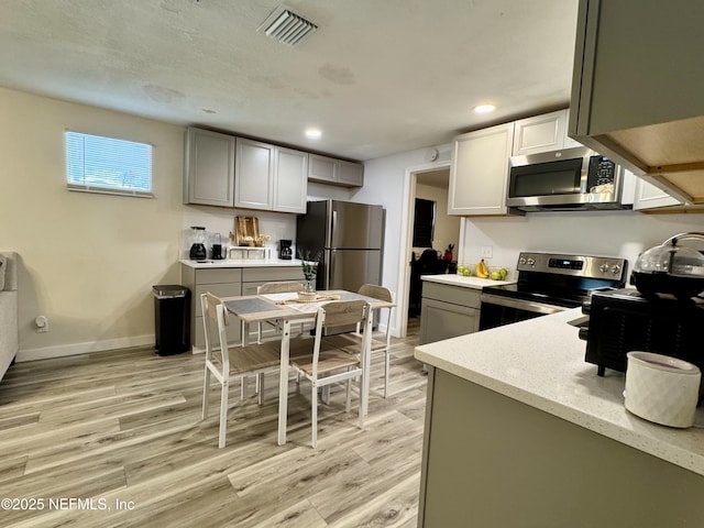 kitchen featuring recessed lighting, light stone counters, visible vents, light wood-style floors, and stainless steel appliances