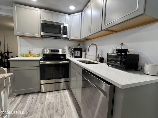 kitchen featuring a sink, stainless steel appliances, light wood-type flooring, recessed lighting, and gray cabinetry