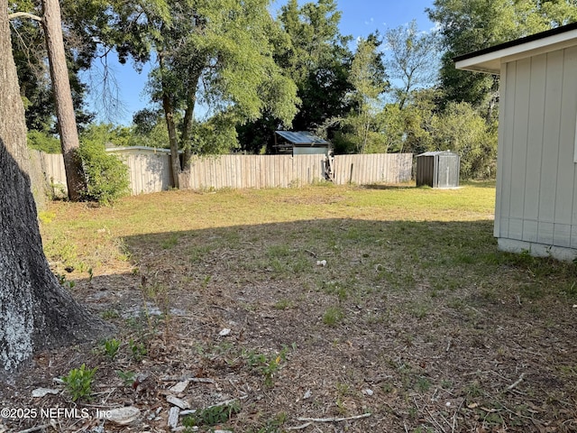 view of yard with a fenced backyard, an outdoor structure, and a storage shed