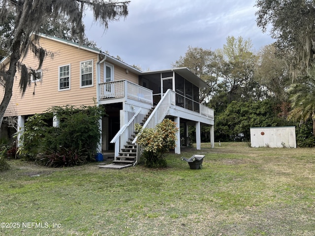 back of property with a sunroom, stairs, and a lawn