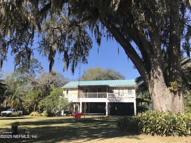 view of front of property with stairs, metal roof, and a front yard