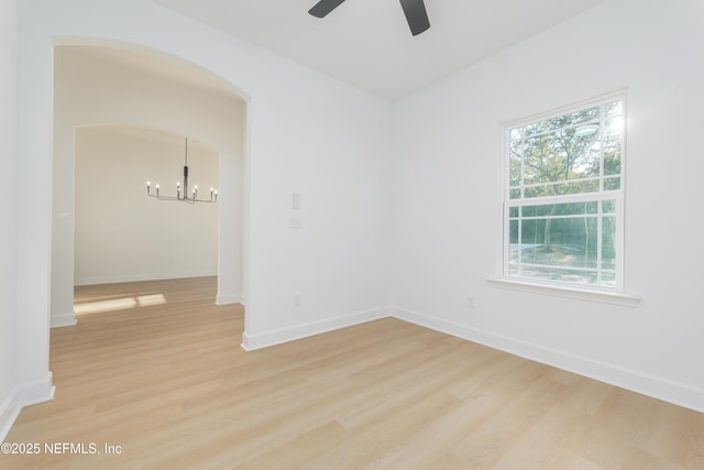 5821 Silver Sands Cir, Keystone Heights, FL 32656 - unfurnished room with ceiling fan with notable chandelier, light wood-type flooring, baseboards, and arched walkways