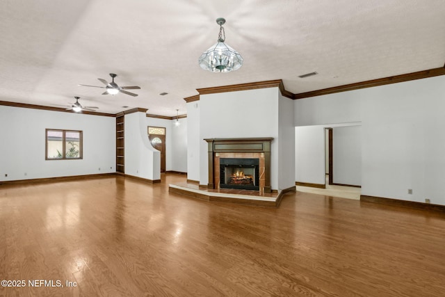 1315 Autumn Trce, Fernandina Beach, FL 32034 - unfurnished living room featuring wood finished floors, a tiled fireplace, crown molding, visible vents, and ceiling fan