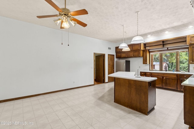 1315 Autumn Trce, Fernandina Beach, FL 32034 - kitchen featuring freestanding refrigerator, light countertops, a kitchen island with sink, and a textured ceiling