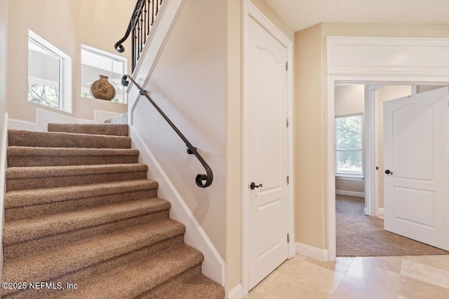 stairway featuring baseboards and carpet floors