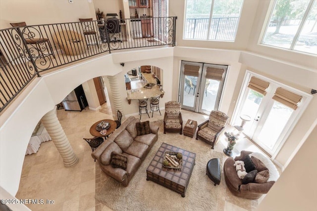 living room featuring tile patterned flooring, a towering ceiling, arched walkways, and french doors