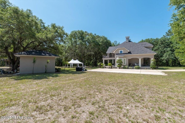 view of green lawn with a gazebo and view of wooded area
