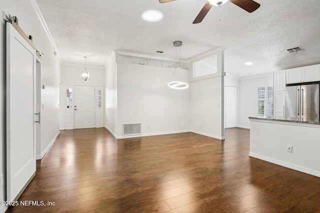 unfurnished living room featuring a textured ceiling, ornamental molding, dark wood-style flooring, ceiling fan, and baseboards