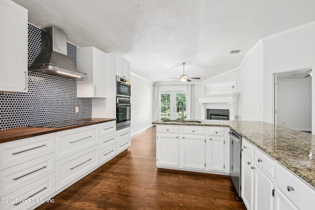 kitchen with a ceiling fan, wall chimney range hood, a sink, crown molding, and dishwasher