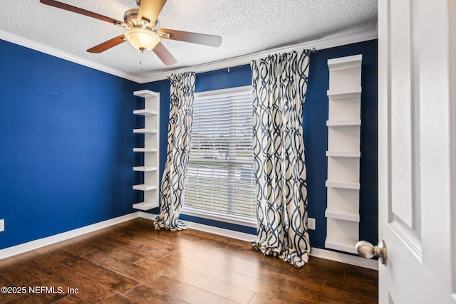 empty room with a textured ceiling, baseboards, dark wood-style flooring, a ceiling fan, and crown molding