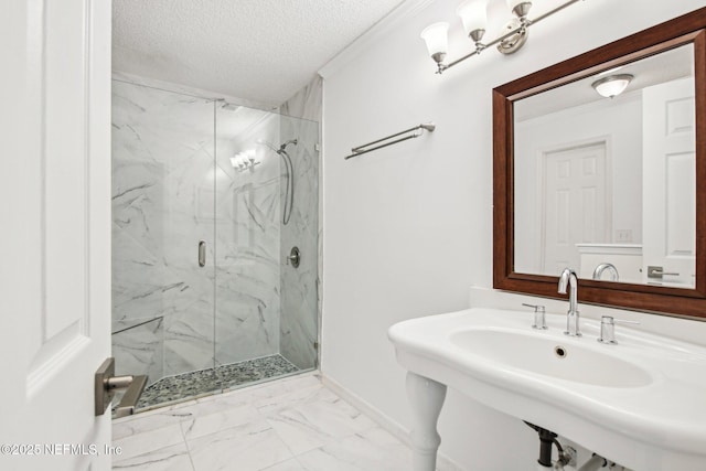 bathroom featuring marble look tiles, a textured ceiling, a marble finish shower, a sink, and baseboards