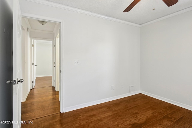 empty room featuring dark wood-type flooring, a ceiling fan, ornamental molding, baseboards, and a textured ceiling