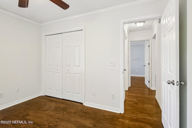 unfurnished bedroom featuring dark wood finished floors, crown molding, baseboards, a closet, and a textured ceiling