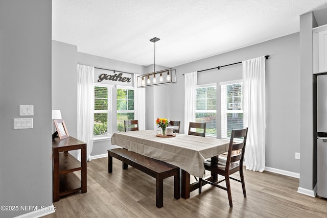 dining area featuring light wood-style flooring, baseboards, a chandelier, and plenty of natural light