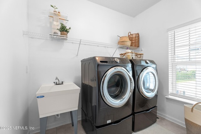 laundry area featuring washer and dryer, light tile patterned floors, and baseboards