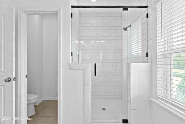 bathroom with tile patterned flooring, healthy amount of natural light, a stall shower, and toilet