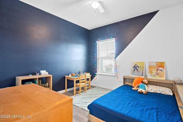 bedroom featuring baseboards, wood finished floors, and a ceiling fan