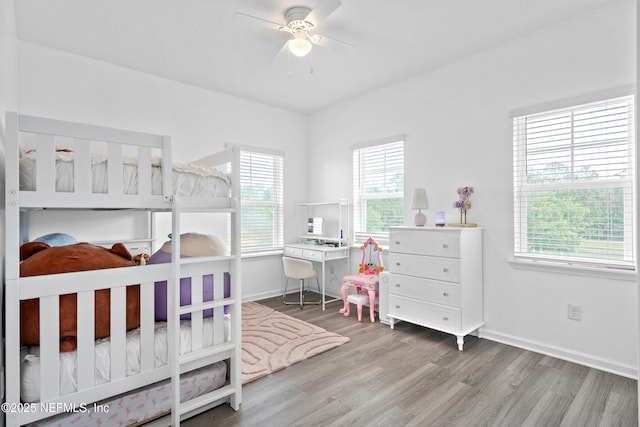 bedroom with multiple windows, wood finished floors, baseboards, and a ceiling fan