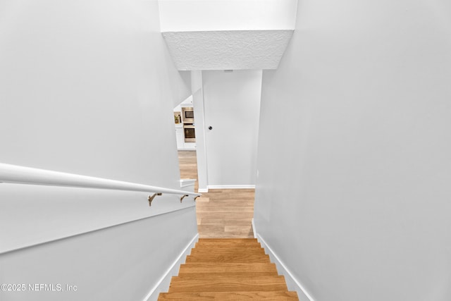 staircase with wood finished floors and baseboards
