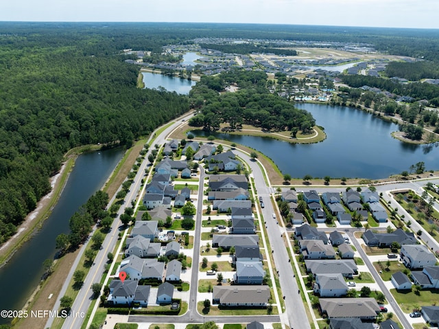 view of property location featuring a forest, nearby suburban area, and a large body of water