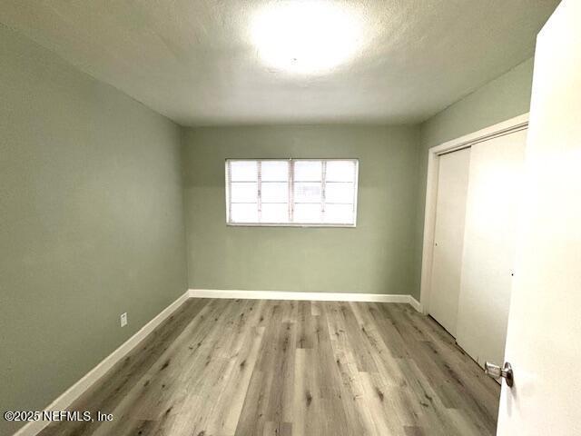 6332 Badnur Dr, Jacksonville, FL 32210 - unfurnished bedroom featuring wood finished floors, a closet, and baseboards