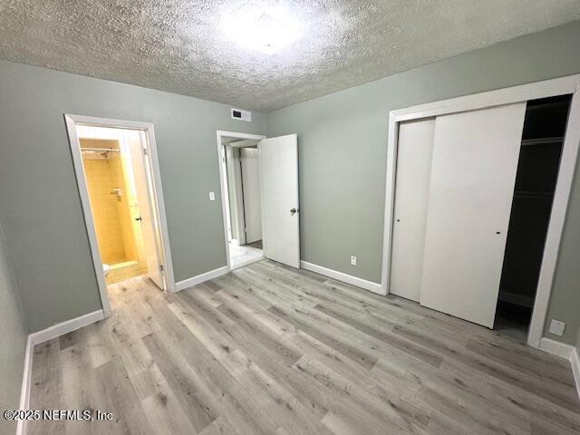 6332 Badnur Dr, Jacksonville, FL 32210 - unfurnished bedroom featuring light wood-style flooring, a closet, a textured ceiling, baseboards, and ensuite bathroom