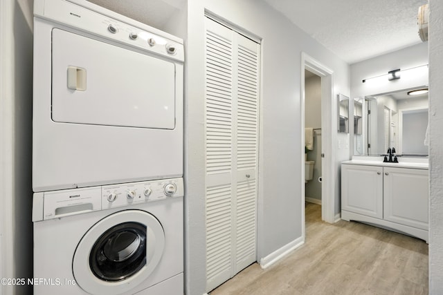 100 Fairway Park Blvd Unit 1809, Ponte Vedra Beach, FL 32082 - clothes washing area with stacked washer / drying machine, light wood-style flooring, baseboards, and a textured ceiling