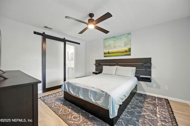 100 Fairway Park Blvd Unit 1809, Ponte Vedra Beach, FL 32082 - bedroom featuring a barn door, light wood-style floors, baseboards, a ceiling fan, and ensuite bath