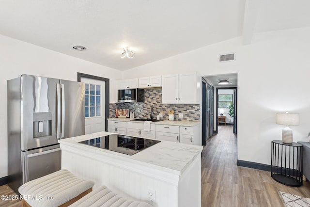 5444 Keystone Dr S, Jacksonville, FL 32207 - kitchen featuring stainless steel appliances, tasteful backsplash, white cabinetry, light countertops, and light wood-type flooring