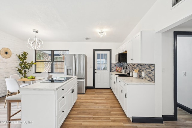 5444 Keystone Dr S, Jacksonville, FL 32207 - kitchen featuring stainless steel fridge with ice dispenser, a sink, black electric stovetop, a breakfast bar, and light wood-style flooring