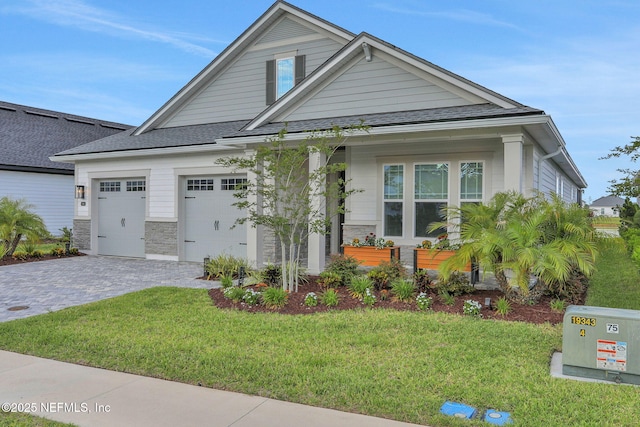 181 Lamego Ln, Saint Augustine, FL 32095 - craftsman inspired home with stone siding, a front yard, an attached garage, decorative driveway, and roof with shingles