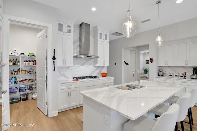 181 Lamego Ln, Saint Augustine, FL 32095 - kitchen featuring a sink, wall chimney exhaust hood, stainless steel gas cooktop, decorative backsplash, and light wood-style floors